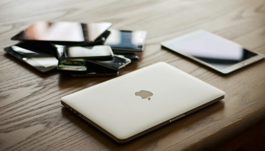 A variety of modern electronic gadgets, including a laptop and smartphones, on a wooden table.